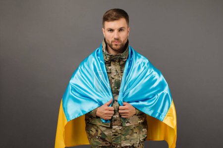 Foto de Retrato de un valiente militar ucraniano sosteniendo la bandera de Ucrania, concepto de libertad - Imagen libre de derechos