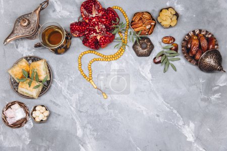 Photo for Stylish banner with traditional Arabic tableware and food sets, cup of tea, Koran and rosary on gray stone background. Ramadan table top view - Royalty Free Image