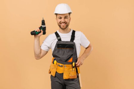 Foto de Reparador masculino positivo en casa sosteniendo un destornillador sobre un fondo beige - Imagen libre de derechos