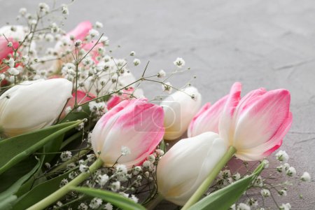 Foto de Tulipanes rosados y ramo de flores de gypsophila blanco sobre un fondo de piedra gris elegante, enfoque selectivo. Día de las Madres, concepto de celebración de cumpleaños. Copiar espacio para texto - Imagen libre de derechos