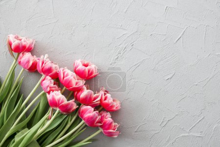 Foto de Ramo de tulipanes rosados sobre un fondo de piedra gris con estilo, enfoque selectivo. Día de las Madres, concepto de celebración de cumpleaños. Copiar espacio para texto - Imagen libre de derechos