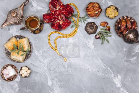 Téléchargez les photos : Élégante bannière avec vaisselle arabe traditionnelle et ensembles de nourriture, tasse de thé, Coran et chapelet sur fond de pierre grise. Ramadan vue de dessus de table - en image libre de droit