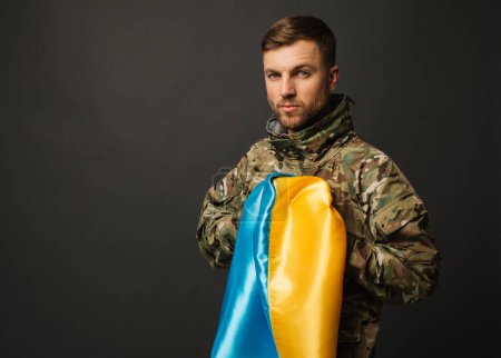 Portrait d'un militaire ukrainien courageux tenant le drapeau de l'Ukraine, concept de liberté