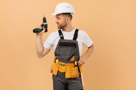 Foto de Reparador masculino positivo en casa sosteniendo un destornillador sobre un fondo beige - Imagen libre de derechos