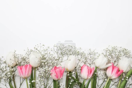 Foto de Tulipanes rosados y ramo de flores de gypsophila blanco sobre un fondo blanco. Día de las Madres, concepto de celebración de cumpleaños. Copiar espacio para texto - Imagen libre de derechos
