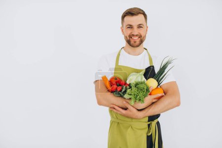 Téléchargez les photos : Homme heureux tenant de nombreux légumes frais différents sur fond blanc - en image libre de droit