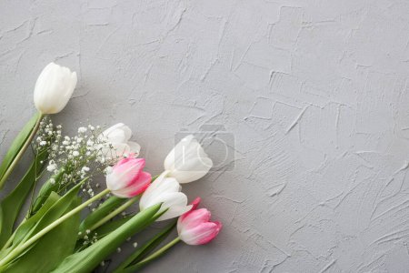 Téléchargez les photos : Bouquet de fleurs de tulipes roses et gypsophiles blanches sur un élégant fond de pierre grise. Fête des Mères, concept de fête d'anniversaire. Espace de copie pour le texte. Maquette - en image libre de droit