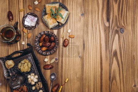 Téléchargez les photos : Dates séchées et thé sur une table en bois. Plats arabes traditionnels, pots et dattes de fruits. Ramadan Kareem, concept Eid Moubarak. Vue de dessus. Pose plate. Espace de copie - en image libre de droit