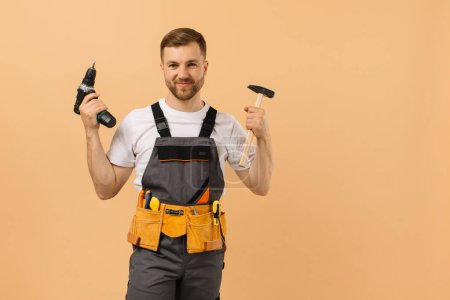 Foto de Reparador masculino positivo en casa con herramientas sobre fondo beige - Imagen libre de derechos