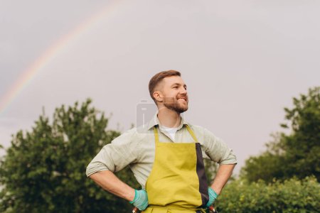 Foto de Retrato de un granjero sonriendo sobre un fondo de arco iris en el jardín - Imagen libre de derechos