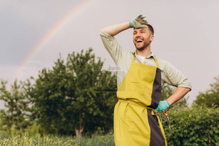 Foto de Retrato de un granjero sonriendo sobre un fondo de arco iris en el jardín - Imagen libre de derechos