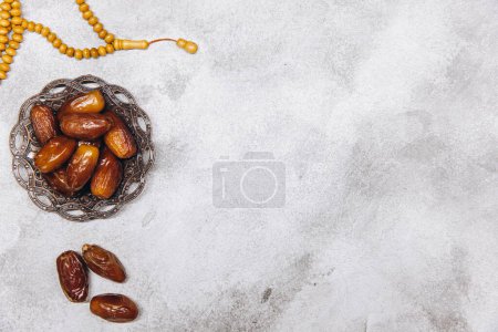 Téléchargez les photos : Image de table de la décoration Ramadan Kareem, dattes fruits et perles de chapelet sur fond gris. Pose plate avec espace de copie. - en image libre de droit
