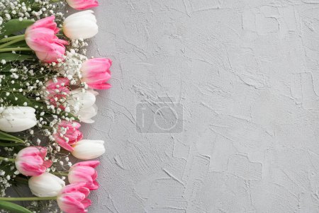 Téléchargez les photos : Bouquet de fleurs de tulipes roses et gypsophiles blanches sur un élégant fond de pierre grise. Fête des Mères, concept de fête d'anniversaire. Espace de copie pour le texte. Maquette - en image libre de droit