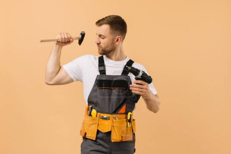 Photo for Positive male repairman at home with tools on beige background - Royalty Free Image