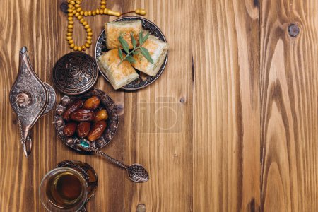 Photo for Ramadan concept, cup of tea, plate of sweet dates and baklava, copy space, top view - Royalty Free Image