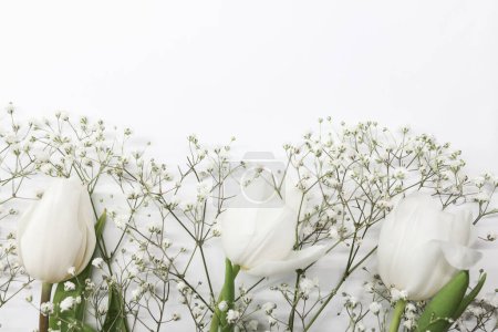 White tulips and gypsophila flowers bouquet on a white background. Mothers Day, birthday celebration concept. Copy space for text