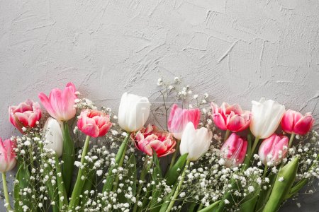 Téléchargez les photos : Bouquet de fleurs de tulipes roses et gypsophiles blanches sur un élégant fond de pierre grise. Fête des Mères, concept de fête d'anniversaire. Espace de copie pour le texte - en image libre de droit