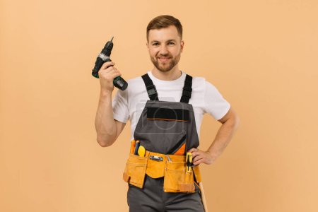 Téléchargez les photos : Réparateur masculin positif à la maison avec tournevis sur fond beige - en image libre de droit