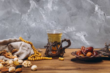 Téléchargez les photos : Concept Ramadan, pochette aux noix éparses, assiette de dattes sucrées et une tasse de thé, espace de copie - en image libre de droit