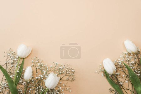 Photo for White tulips and gypsophila flowers bouquet on a beige background. Mothers Day, birthday celebration concept. Copy space for text. Mockup - Royalty Free Image
