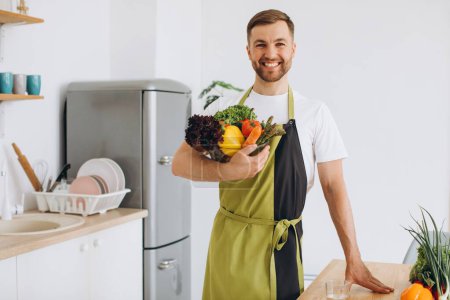 Portrait of a happy man holding a plate of fresh vegetables in the kitchen
