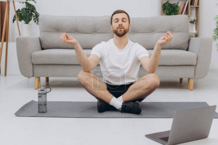 Foto de Mantenga la calma en cuarentena. Millennial chico meditando con entrenador en línea a través de conexión portátil, espacio vacío - Imagen libre de derechos