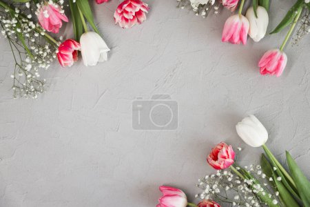 Foto de Tulipanes rosados y ramo de flores de gypsophila blanco sobre un elegante fondo de piedra gris. Día de las Madres, concepto de celebración de cumpleaños. Copiar espacio para texto - Imagen libre de derechos