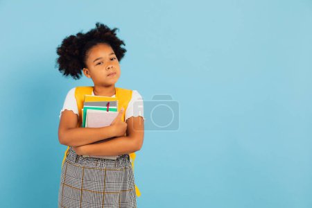Photo for Happy African American schoolgirl holding books on blue background, back to school concept. - Royalty Free Image