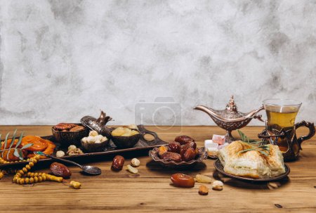 Photo for Dried dates and tea on a wooden table. Arabic traditional dishes, pots and dates fruits. Ramadan Kareem, Eid mubarak concept. Copy space - Royalty Free Image