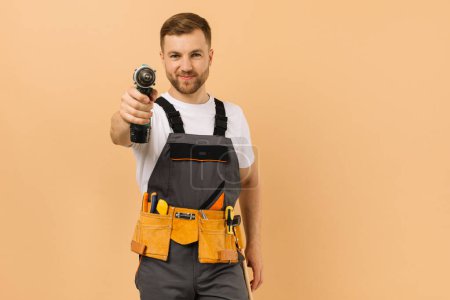 Photo for Positive male repairman at home with screwdriver on beige background - Royalty Free Image
