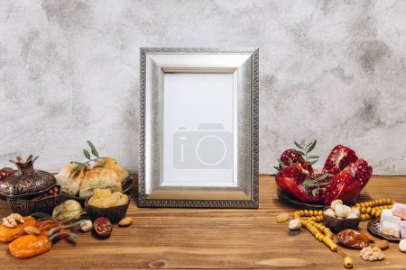 Photo for Composition for Ramadan. Silver frame with copy space or mockup, near traditional islamic tableware with meal on wooden table. - Royalty Free Image
