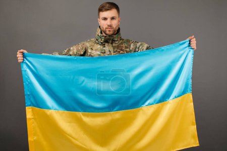 Portrait d'un militaire ukrainien courageux tenant le drapeau de l'Ukraine, concept de liberté