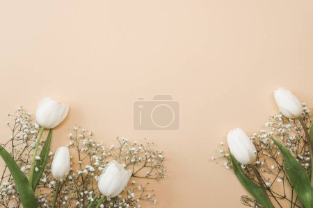 Téléchargez les photos : Bouquet de fleurs de tulipes blanches et gypsophiles sur fond beige. Fête des Mères, concept de fête d'anniversaire. Espace de copie pour le texte. Maquette - en image libre de droit