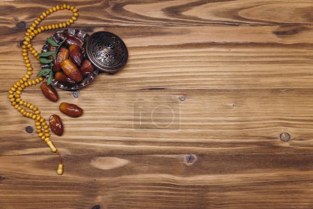 Téléchargez les photos : Image de table de décoration Ramadan Kareem, dattes fruits et perles de chapelet sur fond en bois. Pose plate avec espace de copie. - en image libre de droit