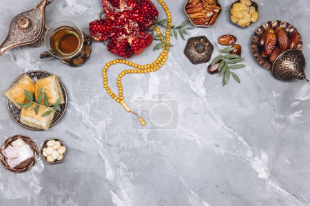 Photo for Stylish banner with traditional Arabic tableware and food sets, cup of tea, Koran and rosary on gray stone background. Ramadan table top view - Royalty Free Image