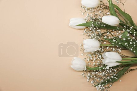 Foto de Tulipanes blancos y ramo de flores de gypsophila sobre un fondo beige. Día de las Madres, concepto de celebración de cumpleaños. Copia espacio para texto. Burla. - Imagen libre de derechos