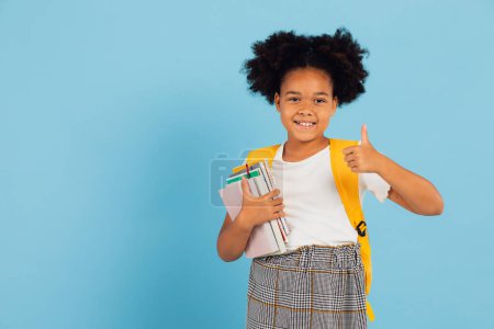 Photo for Happy African American schoolgirl pointing cool on blue background, back to school concept. - Royalty Free Image