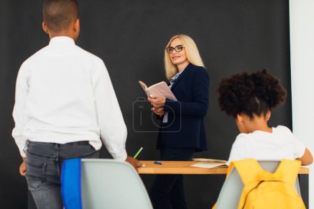 Photo for A girl and a boy, African-American school children, solve problems with the teacher during a lesson. Back to school. - Royalty Free Image