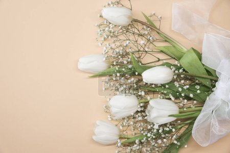 Téléchargez les photos : Bouquet de fleurs de tulipes blanches et gypsophiles sur fond beige. Fête des Mères, concept de fête d'anniversaire. Espace de copie pour le texte. Maquette - en image libre de droit