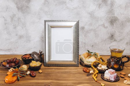 Foto de Composición para Ramadán. Marco de plata con espacio de copia o maqueta, cerca de la vajilla islámica tradicional con comida en mesa de madera. - Imagen libre de derechos