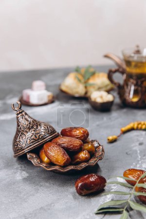Photo for Ramadan table, dates on the background of traditional dishes with dried fruits, fresh garnet, tea. - Royalty Free Image