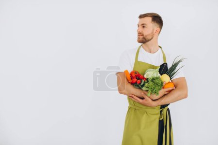 Photo for Happy man holding many different fresh vegetables on white background - Royalty Free Image