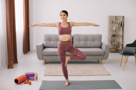 Foto de Mujer joven atractiva y saludable haciendo ejercicios de yoga mientras descansa en casa - Imagen libre de derechos
