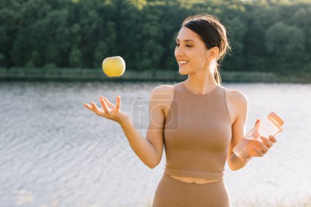 Téléchargez les photos : Heureuse femme sportive tenant la pomme en plein air - en image libre de droit