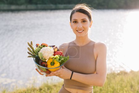 Photo for Portrait of happy vegan woman holding plate of fresh vegetables outdoors - Royalty Free Image