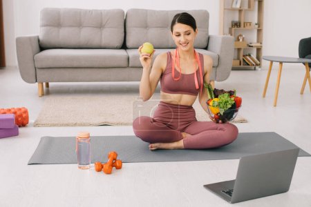Photo for Athletic young woman blogger nutritionist holds vegetables and leads a video call on proper nutrition - Royalty Free Image