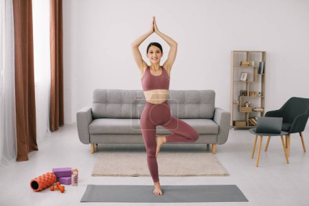 Foto de Mujer joven atractiva y saludable haciendo ejercicios de yoga mientras descansa en casa - Imagen libre de derechos