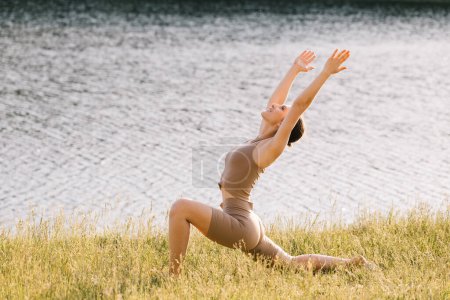 Photo for Happy woman practicing yoga on the outdoors by the river - Royalty Free Image