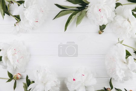 Téléchargez les photos : Pivoines blanches sur un fond en bois blanc, espace de copie, pose plate, carte de vœux. - en image libre de droit