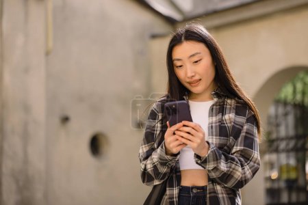 Foto de Retrato de una hermosa mujer coreana en la calle del casco antiguo. Mujer asiática en ropa casual hablando por teléfono, tecnología moderna y estilo de vida. - Imagen libre de derechos